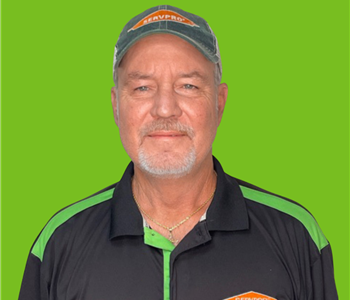 Male employee with a hat on smiling in front of a green background
