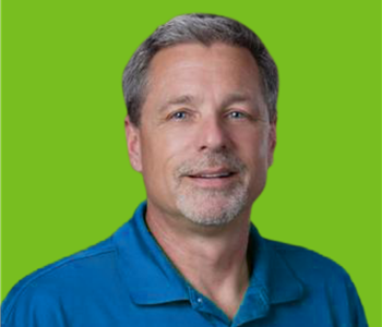 Male employee with grey hair smiling in front of a green background