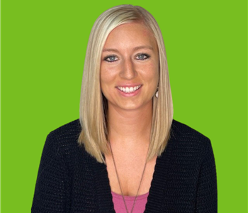Female employee with blonde hair smiling in front of a green background